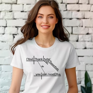 May include: White t-shirt with black text that reads "(You) Thank tutor an Essentials if you can read this". The shirt has a crew neck and short sleeves. The text is arranged in a diagram-like format.