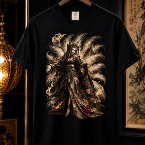 Può includere: Una t-shirt nera a maniche corte con una stampa grafica dettagliata di uno spirito volpe a più code che indossa un kimono scuro a motivi. Il design include code fluenti, accenti floreali e motivi a teschio nei toni dell'oro, del rosso e del bianco.