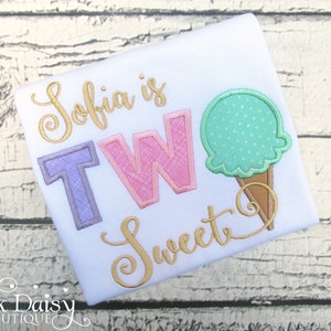 May include: White t-shirt with the text "Sofia is TWO Sweet" in gold script and a pink and purple "TWO" with a green ice cream cone graphic.