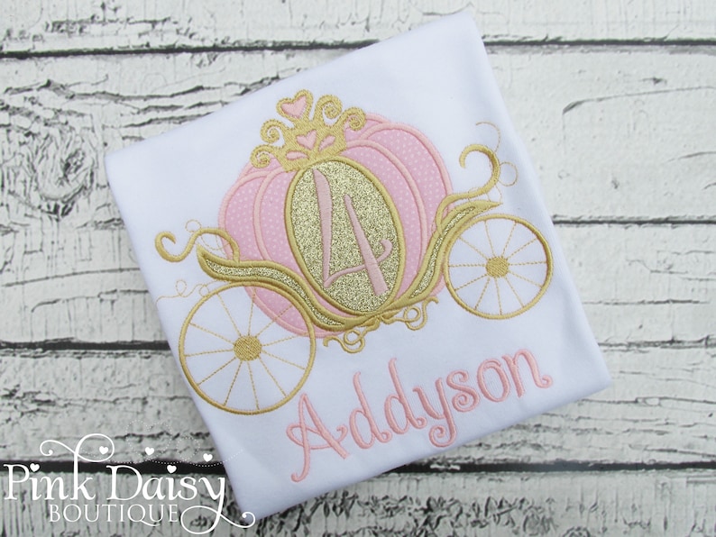 May include: A white t-shirt with a pink and gold embroidered pumpkin carriage and the name Addyson.