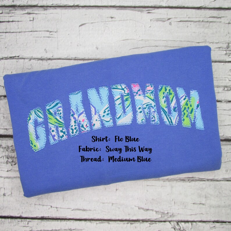 May include: A blue shirt with the word "GRANDMOM" in a floral pattern. The shirt's color is "Flo Blue", the fabric is "Sway This Way", and the thread is "Medium Blue".