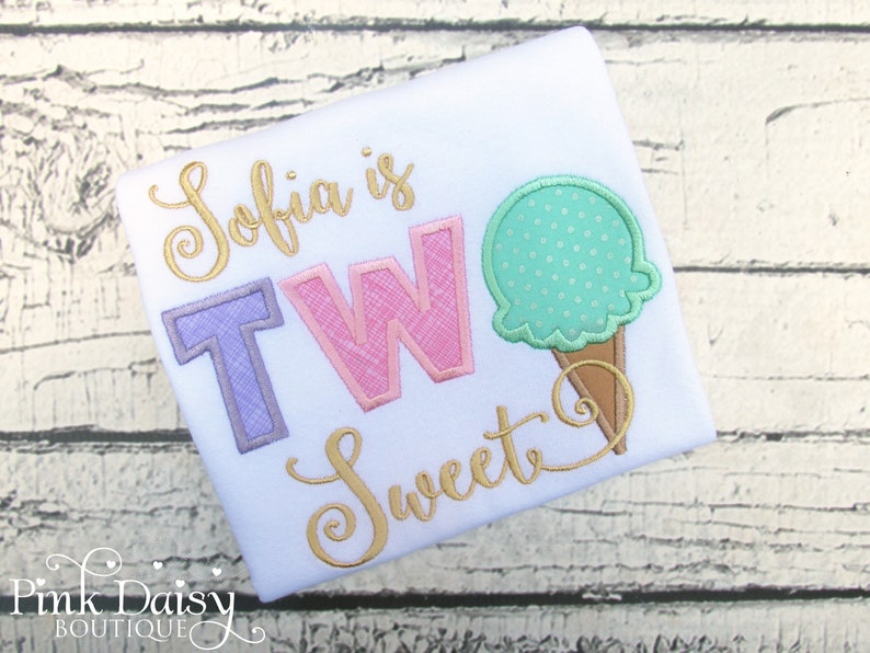 May include: White t-shirt with the text "Sofia is TWO Sweet" in gold script and a pink and purple "TWO" with a green ice cream cone graphic.