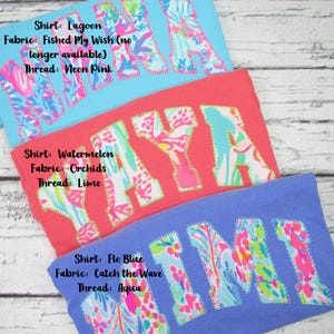 May include: Three colorful t-shirts with embroidered names. The top shirt is light blue with pink stitching and the name "MAYA". The middle shirt is red with lime stitching and the name "MAYA". The bottom shirt is blue with aqua stitching and the name "MIMI".