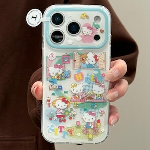 Puede incluir: Funda transparente para tel&eacute;fono con un dise&ntilde;o colorido de Hello Kitty. La funda tiene un borde azul claro e incluye ilustraciones de Hello Kitty en varias escenas, con la palabra "Kitty" en la parte inferior. La funda la sostiene una persona.