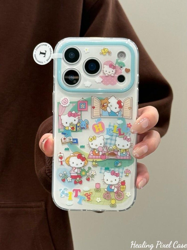 Puede incluir: Funda transparente para tel&eacute;fono con un dise&ntilde;o colorido de Hello Kitty. La funda tiene un borde azul claro e incluye ilustraciones de Hello Kitty en varias escenas, con la palabra "Kitty" en la parte inferior. La funda la sostiene una persona.