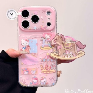 May include: A clear phone case featuring a pink camera frame and various Hello Kitty graphics, including carousel horses and stars. A detachable rocking horse phone grip with internal loose beads is attached to the right side of the case.