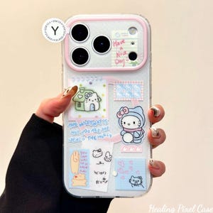 May include: A clear smartphone case featuring a pink camera frame and various stickers including a Hello Kitty character, a small house, a notepad with the text Have a Nice Day, and the phrase The Milkyway is hot you are the ideal of the world.