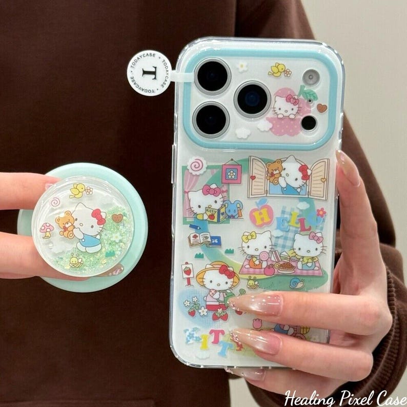 Puede incluir: Funda transparente para tel&eacute;fono con borde azul claro y un pop socket a juego. La funda presenta un colorido dise&ntilde;o de Hello Kitty con varias escenas. El pop socket tiene un interior brillante con un dise&ntilde;o de Hello Kitty y oso.
