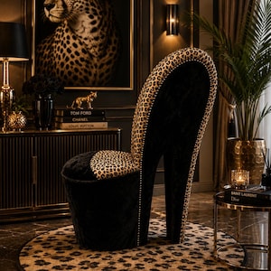 May include: A high-heeled shoe shaped chair upholstered in black velvet and leopard print fabric. The backrest and seat feature a leopard pattern, while the base and heel are covered in black velvet. The edges are accented with small metallic studs.