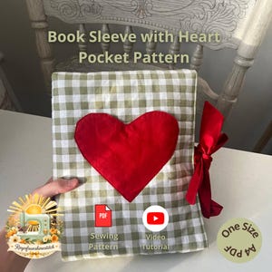 May include: A handmade book sleeve with a red heart-shaped pocket on a green and white checkered pattern. The text "Book Sleeve with Heart Pocket Pattern" is visible. A red ribbon is tied on the side. Includes a sewing pattern and video tutorial.