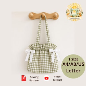 May include: A sage green and white gingham tote bag with a ruffled top edge and two white ribbon bows on the sides. The bag hangs from a wooden hook. Text on the image includes 1 SIZE A4/A0/US Letter, Sewing Pattern, and Video Tutorial.