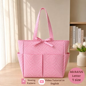 Puede incluir: Un bolso tote de cuadros vichy rosa y blanco con dos asas superiores, un detalle de lazo decorativo en el centro y dos grandes bolsillos exteriores. El bolso se presenta con texto que indica un patrón de costura PDF y un tutorial en inglés.
