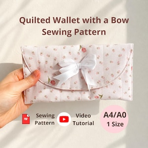 Może przedstawiać: Wykrój do szycia pikowanego portfela z jasnoróżowej tkaniny w drobne kwiaty z białą kokardką na przedniej klapie. Tekst głosi Quilted Wallet with a Bow Sewing Pattern, PDF, Sewing Pattern, Video Tutorial oraz A4/A0 1 Size.