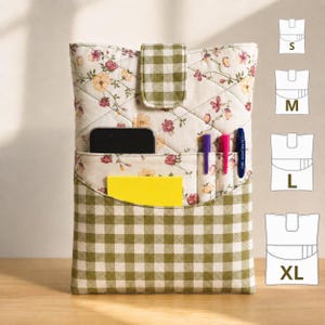 May include: A quilted fabric pouch featuring a floral pattern on a cream background with a green and white gingham flap closure. The front pocket holds a black smartphone, a yellow notepad, and two pens. Size chart icons for S, M, L, and XL are visible.