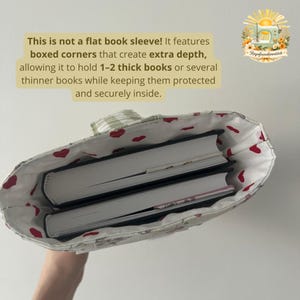 May include: A fabric book sleeve with boxed corners for extra depth, containing two thick books. The interior lining is white with a red heart pattern. Text on the image reads: This is not a flat book sleeve! It features boxed corners that create extra depth, allowing it to hold 1-2 thick books or several thinner books while keeping them protected and securely inside.