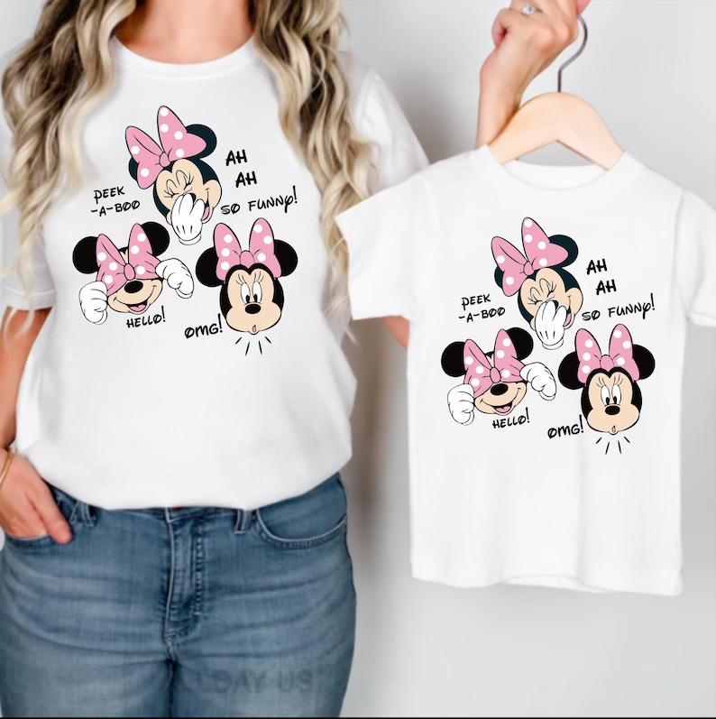 Op de afbeelding: Witte T-shirts met een Minnie Mouse-afbeelding. De afbeelding toont Minnie Mouse met een roze strik en de zinnen "Peek-a-boo", "Hello!", "OMG!" en "Ah, ah, so funny!" op de shirts.