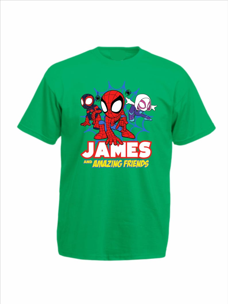 May include: A bright green short-sleeve t-shirt featuring a graphic of three cartoon superheroes in front of a blue spiderweb. Below the characters, the text reads JAMES AND AMAZING FRIENDS in bold white and yellow lettering on the front.