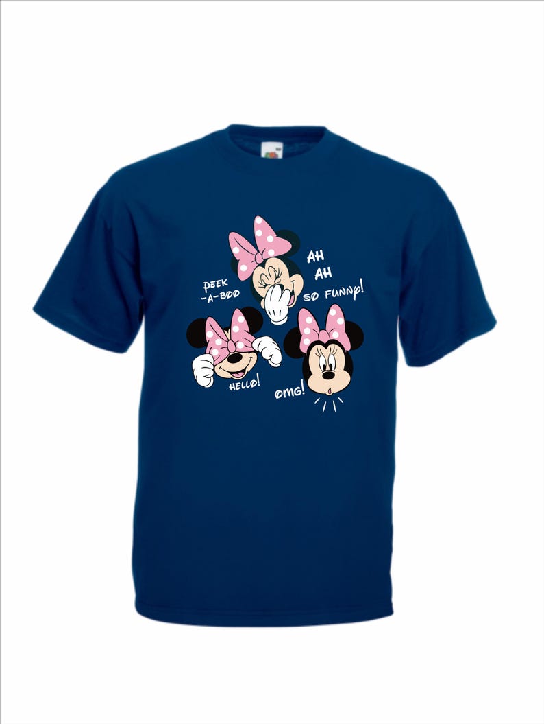 Op de afbeelding: Marineblauw T-shirt met een Minnie Mouse-ontwerp. Het ontwerp bevat Minnie Mouse met roze strikken en de zinnen "Peek-a-boo", "Hello!" en "Ah, ah, so funny!" in witte tekst. Het cartoonontwerp is gecentreerd.