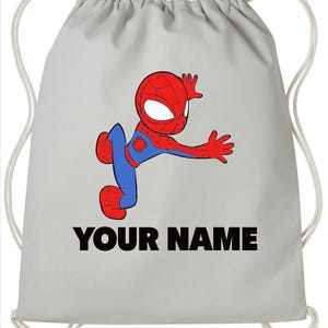 May include: A light grey drawstring backpack featuring a cartoon illustration of a red and blue superhero character in a dynamic pose. Below the character, the text "YOUR NAME" is printed in bold, black, sans-serif capital letters.