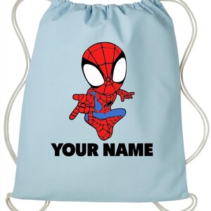 May include: A light blue drawstring backpack featuring a cartoon illustration of a red and blue spider-themed character in a crouching pose. Below the character, the text "YOUR NAME" is printed in bold, black, capital letters on the fabric.