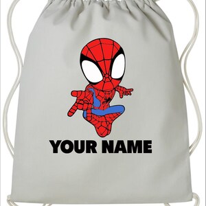 May include: A light gray drawstring backpack featuring a cartoon illustration of a red and blue superhero character with large white eyes. Below the character, the text "YOUR NAME" is printed in bold, black, capital letters on the bag surface.