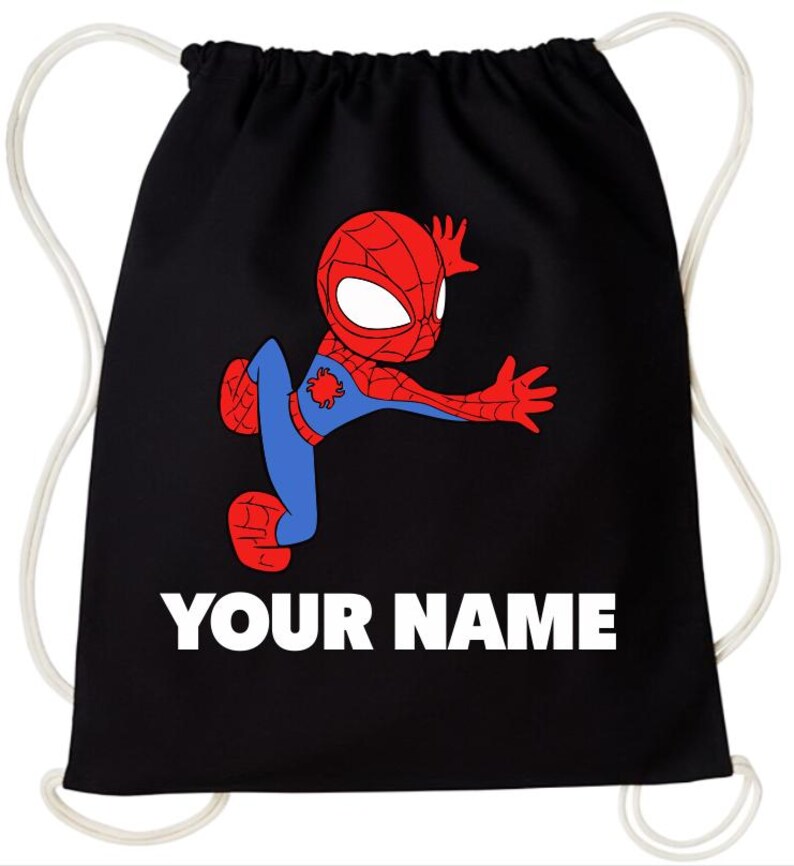 May include: A black drawstring backpack featuring a graphic of a red and blue cartoon superhero in a dynamic pose. Below the character, the text "YOUR NAME" is printed in bold white capital letters. The bag has white cord straps on both sides.