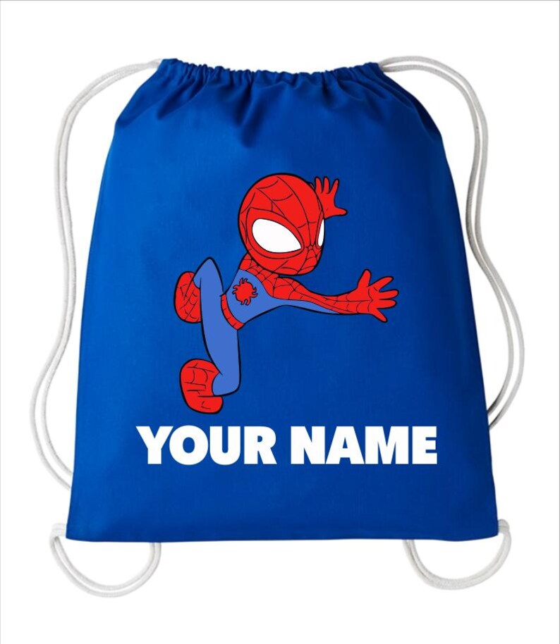 May include: A royal blue drawstring bag featuring a cartoon illustration of a red and blue superhero character in a dynamic pose. Below the character, the text "YOUR NAME" is printed in bold, white, capital letters. The bag has white cords.