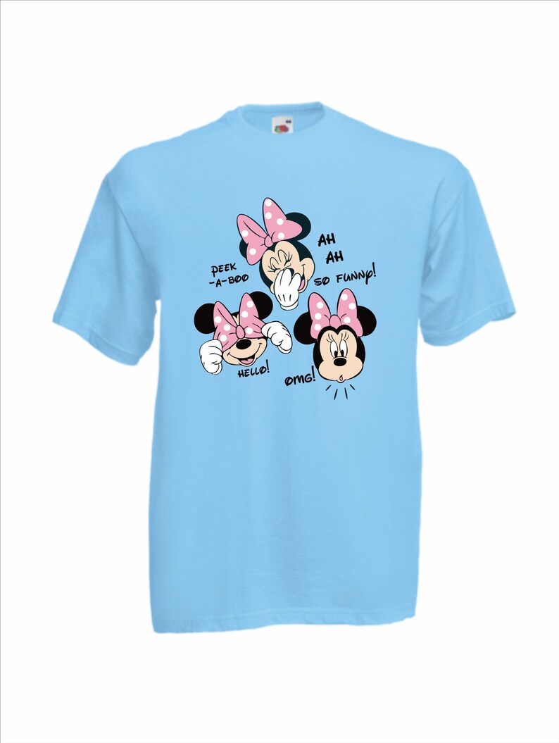 Op de afbeelding: Lichtblauw T-shirt met een Minnie Mouse-afbeelding. De afbeelding toont Minnie met roze strikken en de zinnen "Peek-a-boo", "Hello!", "Ah Ah So Funny!" en "OMG!" in zwarte tekst.