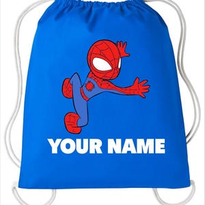 May include: A bright blue drawstring bag featuring a cartoon illustration of a red and blue superhero character in a dynamic pose. Below the character, the text YOUR NAME is printed in bold white capital letters. The bag has white cord straps.