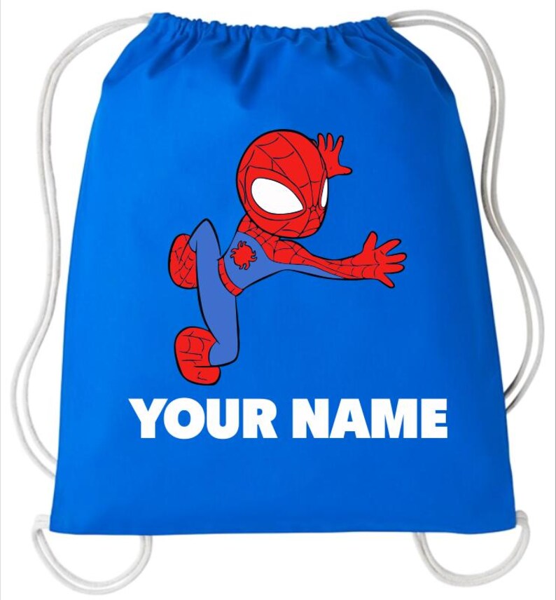 May include: A bright blue drawstring bag featuring a cartoon illustration of a red and blue superhero character in a dynamic pose. Below the character, the text YOUR NAME is printed in bold white capital letters. The bag has white cord straps.