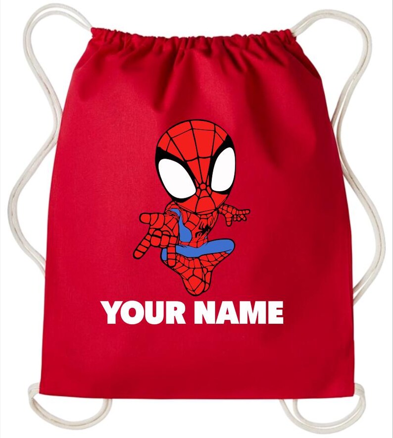 May include: A bright red drawstring backpack featuring a cartoon illustration of a spider-themed superhero in a crouching pose. Below the character, the text "YOUR NAME" is printed in bold white capital letters. The bag has white cord straps.
