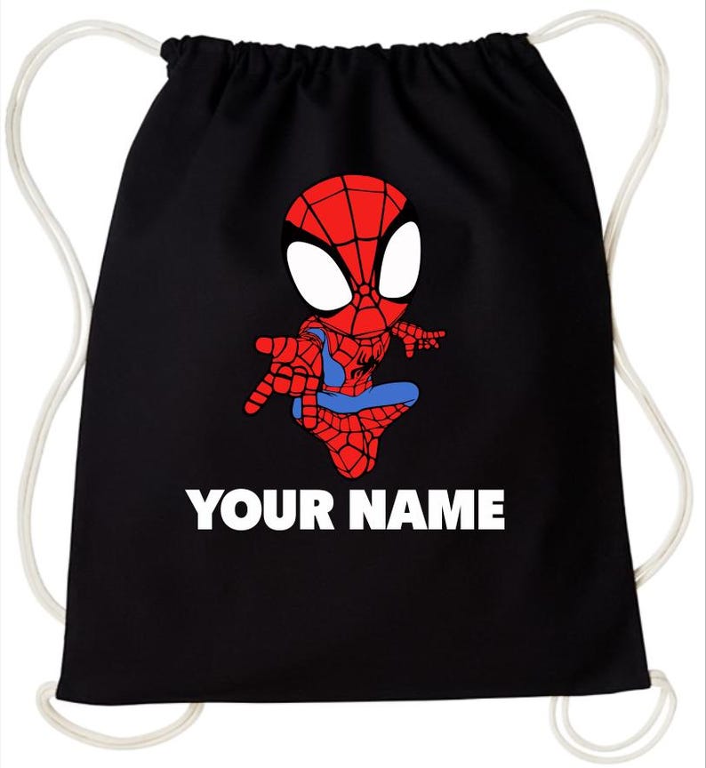 May include: A black drawstring backpack featuring a graphic of a cartoon superhero with a red and blue suit and large white eyes. Below the character, the text YOUR NAME is printed in bold white capital letters. The bag has white cord straps.