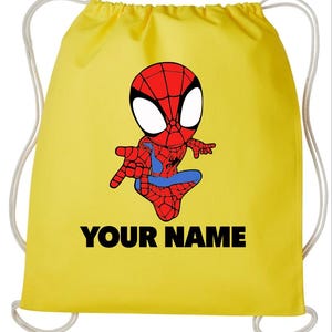 May include: A bright yellow drawstring backpack featuring a cartoon illustration of a red and blue spider-themed character with large white eyes. The text "YOUR NAME" is printed in bold black capital letters below the character graphic.