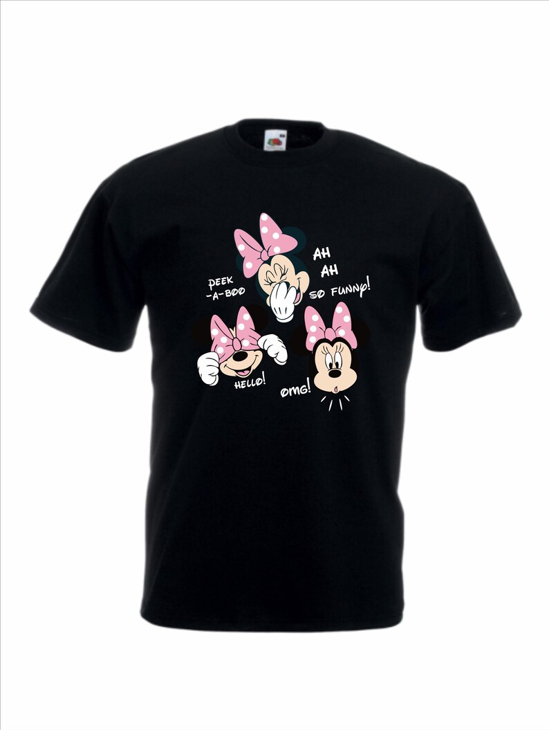 Op de afbeelding: Zwart T-shirt met een Minnie Mouse-ontwerp. Het ontwerp toont Minnie in drie verschillende poses, elk met een roze strik en tekstballonnen met de tekst "Peek-a-boo", "Hello!", "Ah, ah, so funny!" en "omg!".