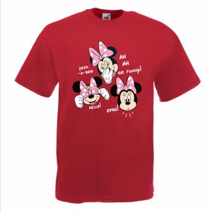 Op de afbeelding: Rood T-shirt met een Minnie Mouse-afbeelding. De afbeelding toont Minnie Mouse in drie verschillende poses met tekstballonnen met de tekst "Peek-a-boo", "Hello!", "Ah, Ah, So Funny!" en "Omg!". Het shirt heeft korte mouwen.