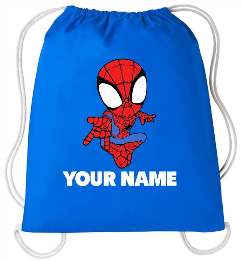 May include: A bright blue drawstring bag featuring a cartoon illustration of a red and blue superhero character with large white eyes. Below the character, the text YOUR NAME is printed in bold white capital letters. The bag has white cords.
