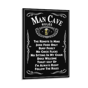Può includere: Una targa da parete rettangolare nera con bordi decorativi bianchi e il testo Man Cave Rules. Al centro è presente un'immagine di un boccale di birra giallo. Il testo elenca regole come The Remote Is Mine, Junk Food Only, Burp Freely, No Chick Flicks, No Sitting In My Chair, Dogs Welcome, Toilet Seat Up, I'm Always Right e Follow The Rules.