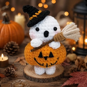 May include: A crocheted ghost figure wearing a black witch hat with an orange band, holding a small tan broom. The ghost sits atop a round, orange crocheted pumpkin with a black stitched jack-o'-lantern face, all resting on a wooden base.