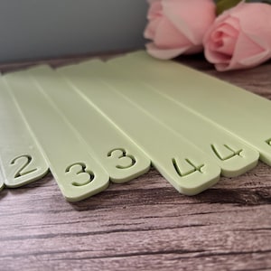 May include: A set of pale green rectangular plastic dividers, each featuring a die-cut number. The sequence includes two 2s, two 3s, two 4s, and two 5s, arranged in a fan-like formation with rounded corners on the bottom edges of each piece.