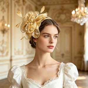 Könnte beinhalten: Ein goldener Fascinator-Kopfschmuck mit geschichteten, durchscheinenden, bandartigen Stoffblütenblättern, die in einer großen, kreisförmigen Blumenform angeordnet sind, mit zarten, dünnen Federn, befestigt an einem dünnen, passenden goldenen Haarreif.