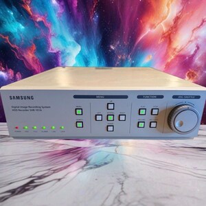 May include: A light grey Samsung Digital Image Recording System HDD Recorder SHR-101A with a front control panel featuring multiple square buttons, green status indicator lights, and a circular jog-shuttle dial on the right side of the device.
