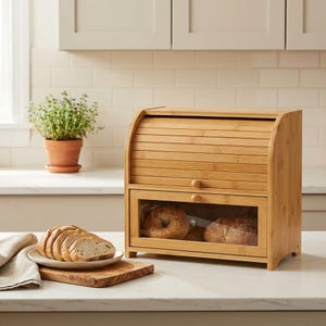 May include: A light brown bamboo bread box with a roll-top lid and a lower drawer featuring a clear glass window. The bread box is constructed with horizontal slats and small round wooden knobs for opening the lid and the drawer.