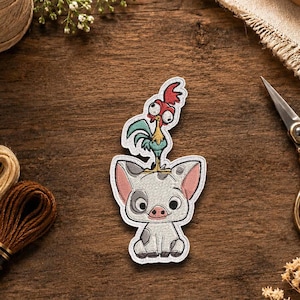 May include: An embroidered patch featuring a cartoon pig with gray spots and pink ears, with a small red and green rooster standing on its head. The patch has a white border and is displayed on a dark wooden surface with embroidery supplies.