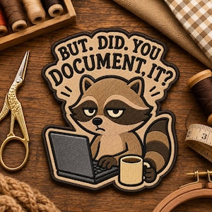May include: An embroidered patch featuring a cartoon raccoon sitting at a laptop with a coffee mug. The text reads, "BUT. DID. YOU. DOCUMENT. IT?" The raccoon has brown fur, a dark mask, and a striped tail. The patch has a dark brown border.