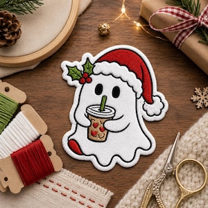 May include: An embroidered patch featuring a white ghost wearing a red and white Santa hat with a green holly sprig. The ghost holds a tan coffee cup decorated with small red hearts and a green straw, outlined in black thread on a white background.