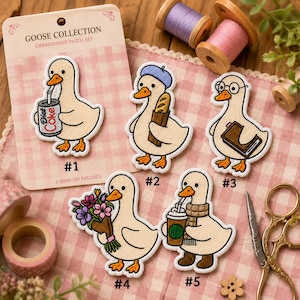 May include: A set of five embroidered iron-on patches featuring cartoon geese on a display card labeled GOOSE COLLECTION. The patches show geese drinking soda, holding a baguette, wearing glasses with a book, holding flowers, and drinking coffee.