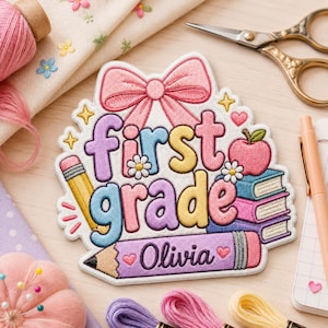 May include: An embroidered patch featuring a pink bow at the top, the text 'first grade' in colorful bubble letters, a yellow pencil, a red apple, and a stack of books. A purple pencil at the bottom displays the name 'Olivia' in black.