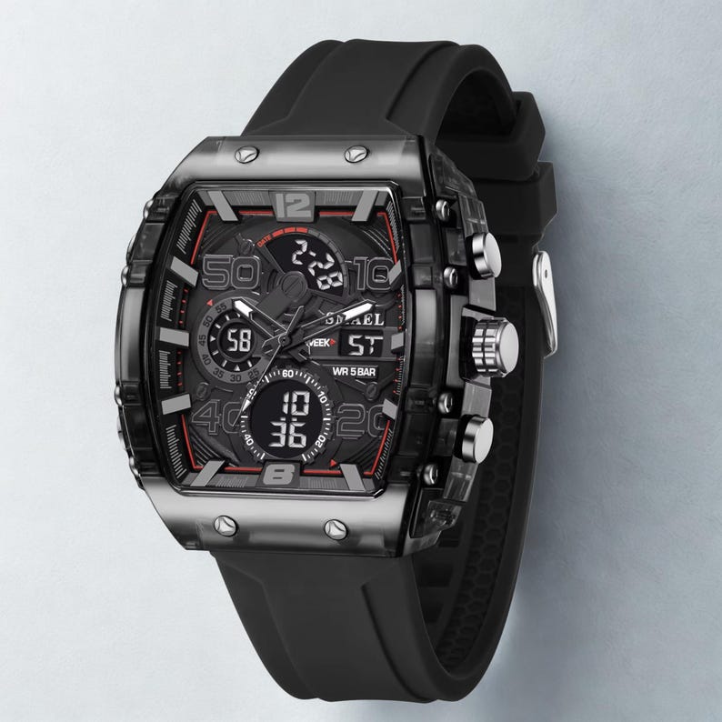 K&ouml;nnte beinhalten: Schwarze Digitaluhr mit rechteckigem Zifferblatt und schwarzem Kautschukarmband. Die Uhr verf&uuml;gt &uuml;ber mehrere digitale Anzeigen mit roten Akzenten und silberfarbenen Kn&ouml;pfen. Das Zifferblatt zeigt die Marke "SMAEL".