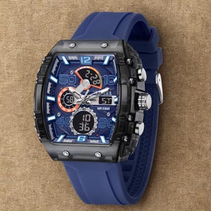 K&ouml;nnte beinhalten: Eine blaue und schwarze Digitalarmbanduhr mit quadratischem Zifferblatt und blauem Silikonarmband. Das Zifferblatt zeigt mehrere digitale Anzeigen und analoge Zeiger. Die Uhr hat silberne Kn&ouml;pfe und eine schwarze L&uuml;nette.