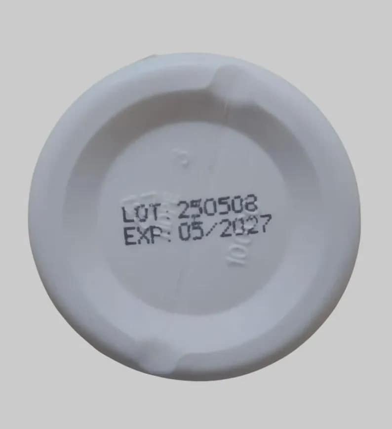 Puede incluir: Tapa de pl&aacute;stico blanco con el texto "LOT: 250508" y "EXP: 05/2027" impreso en negro. La tapa tiene forma circular con un centro rebajado y una superficie ligeramente texturizada.